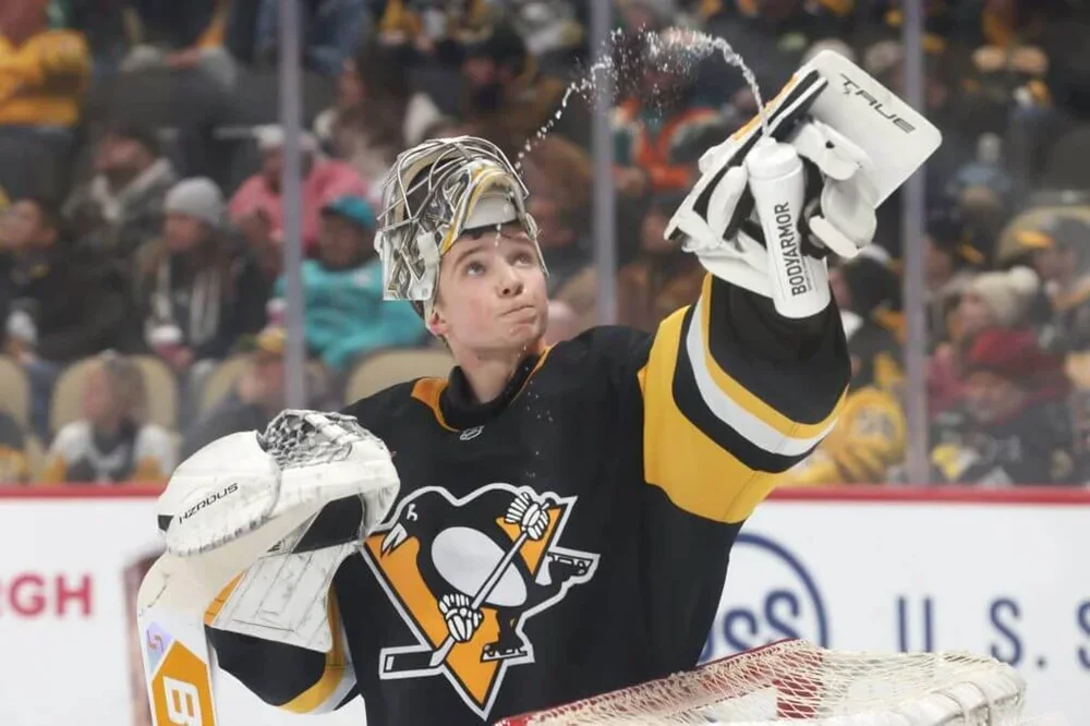 Pittsburgh Penguins goaltender Sergei Murashov sprays water from a bottle into the air during an NHL game.